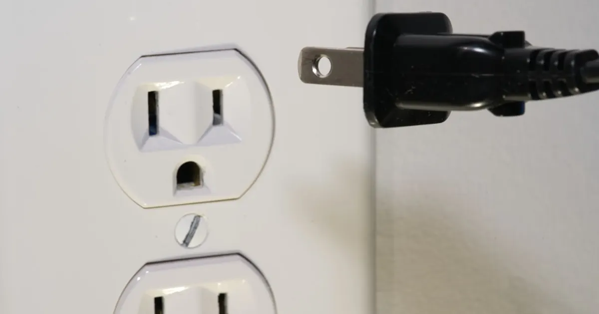 Black male plug in front of electric socket