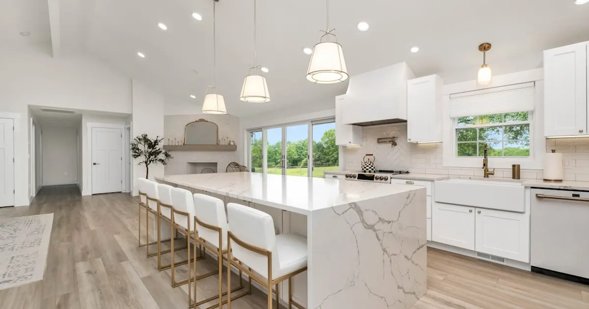 A large kitchen with a marble island and white cabinets