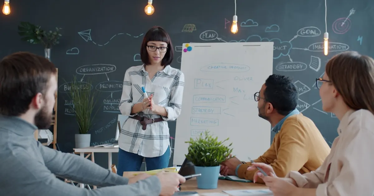 Woman presents to colleagues at a whiteboard meeting.
