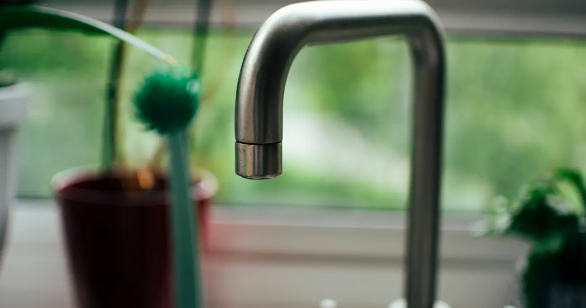 A kitchen sink with a faucet next to a window