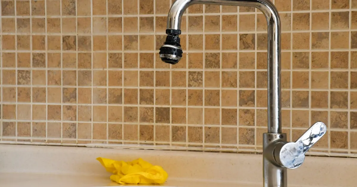 A kitchen sink with a faucet and a yellow sponge
