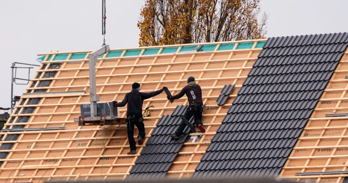 Workers installing roof tiles on a new building.
