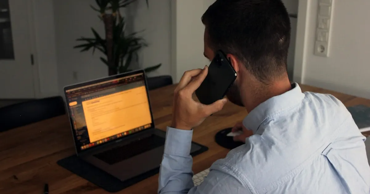 Man in blue dress shirt holding black smartphone